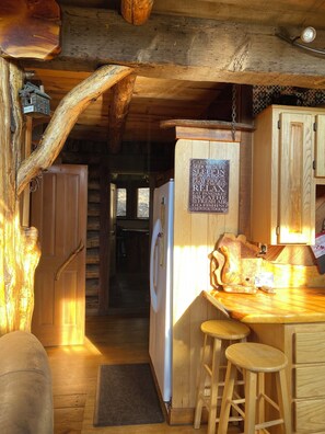 Ein rustikales Blockhaus-Interieur mit einer Holztheke, Barhocker, einem Kühlschrank und einem Schild mit angebotenen Aktivitäten.