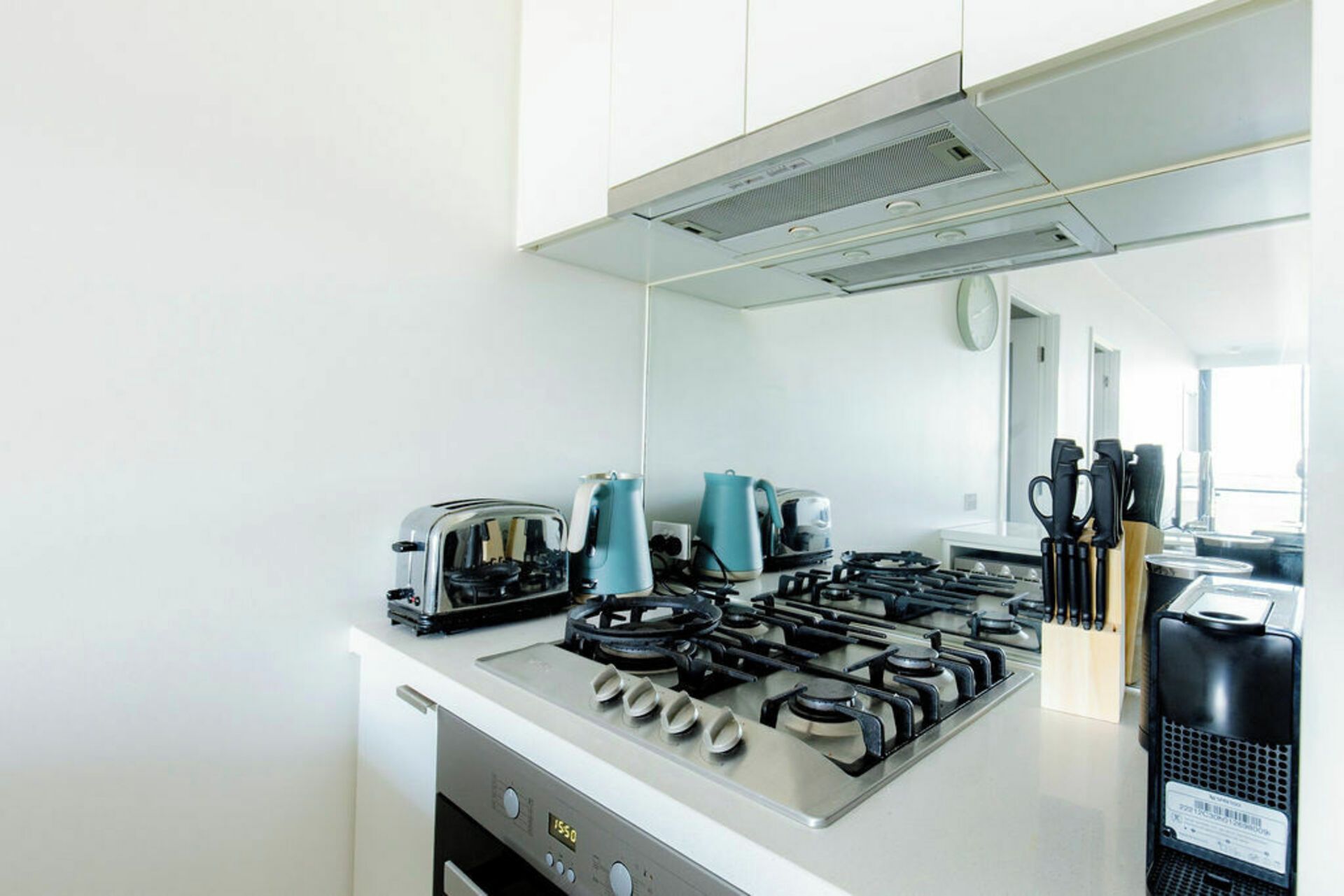 A modern kitchen with a gas stove, a coffee maker, and a kettle.