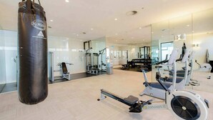 Une salle de sport équipée de machines de cardio, d’appareils de musculation et d’un sac de frappe.