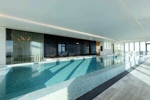 A modern indoor swimming pool with a clear view of the pool, a seating area, and a large window. - Executive 2BDR in Southbank w Parking. (Southbank)