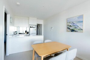 Eine moderne Küche mit weißen Schränken, einem Holztisch und einem Bild an der Wand.