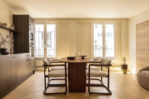 A modern kitchen with a dining table and chairs, large windows, and a view of the city. - Design Appartement a/c 2br/4p - Montmartre (Paris)