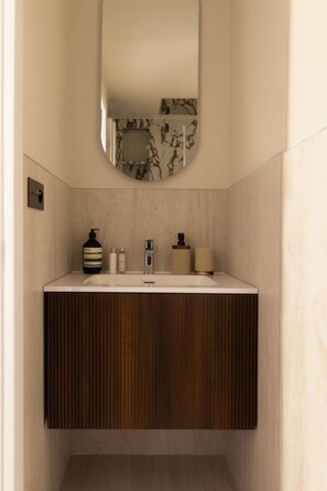 A bathroom with a vanity, a mirror, and toiletries. - Design Appartement a/c 2br/4p - Montmartre (Paris)