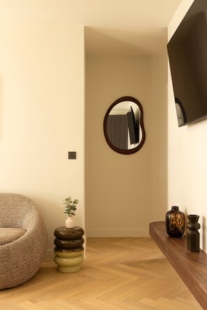 Ein Zimmer mit einem runden Spiegel, einem Sitzsack, einer kleinen Pflanze und einem Holznachttisch mit Vasen.