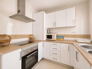 Eine moderne Küche mit weißen Schränken, einer Mikrowelle, einem Backofen und einem Spülbecken.