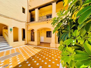 A courtyard with a tiled floor, arches, a staircase, and a balcony. - Max Apartment With Communal Garden and Pool (Roquetas de Mar)
