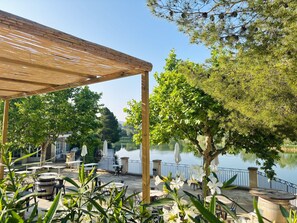 An outdoor patio with tables and chairs, a wooden pergola, and a lake view. - Stay With Private Outdoor Space (Mallemort)