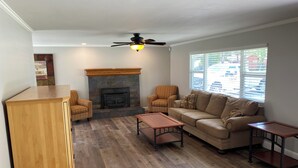 A living room with a fireplace, two sofas, a coffee table, and a ceiling fan. - 3-possible 4 bedroom house in Modesto with plenty parking & space. (Modesto)