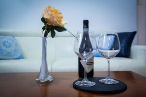 Ein Tisch mit einer Weinflasche, zwei Weingläsern und einer Vase mit einer Blume.