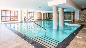 An indoor swimming pool with clear water, a metal ladder, and stone-tiled flooring. - Alps Flat With Heated Pool (Araches-la-Frasse)