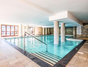 An indoor swimming pool with clear water, a metal ladder, and stone-tiled flooring. - Alps Flat With Heated Pool (Araches-la-Frasse)