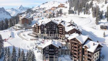 A ski resort with multiple multi-story buildings, ski slopes, and snow-covered trees.