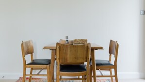 A dining table with four wooden chairs, a woven basket, and a small metal container on the table. - Tasteful 2BDR Midcentury Modern Home (London)