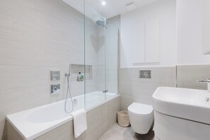 Une salle de bain moderne avec une douche à parois de verre, une baignoire sur pieds et des toilettes blanches.