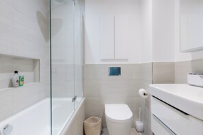 A modern bathroom with a glass-enclosed shower, a toilet, and a sink. - Tasteful 2BDR Midcentury Modern Home (London)
