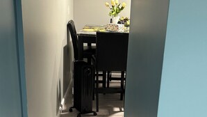 Un pasillo con un tapete estampado, una mesa con un florero y una maleta.