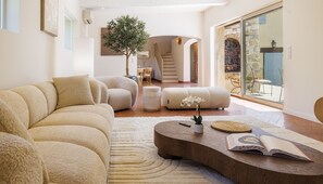 Ein modernes Wohnzimmer mit einer Couch, einem Hocker, einem Couchtisch und einer Topfpflanze mit Orchideen.