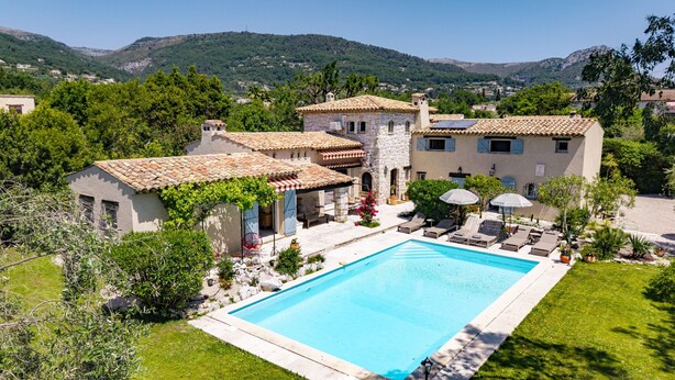 Una villa con piscina, mobiliario exterior y vistas a las colinas circundantes.