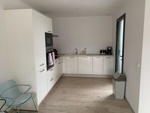 A compact kitchen with white cabinets, a microwave, a coffee maker, and a trash bin. - Lecci Retreat Near Cala Rossa Beach (Lecci)