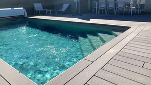 A rectangular swimming pool with clear water, surrounded by a wooden deck and white lounge chairs. - Lecci Retreat Near Cala Rossa Beach (Lecci)