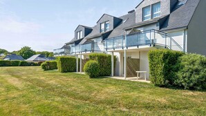 A row of modern houses with balconies, neatly trimmed hedges, and a well-maintained lawn. - Premium 6-person Island Sanctuary (Île-aux-Moines)