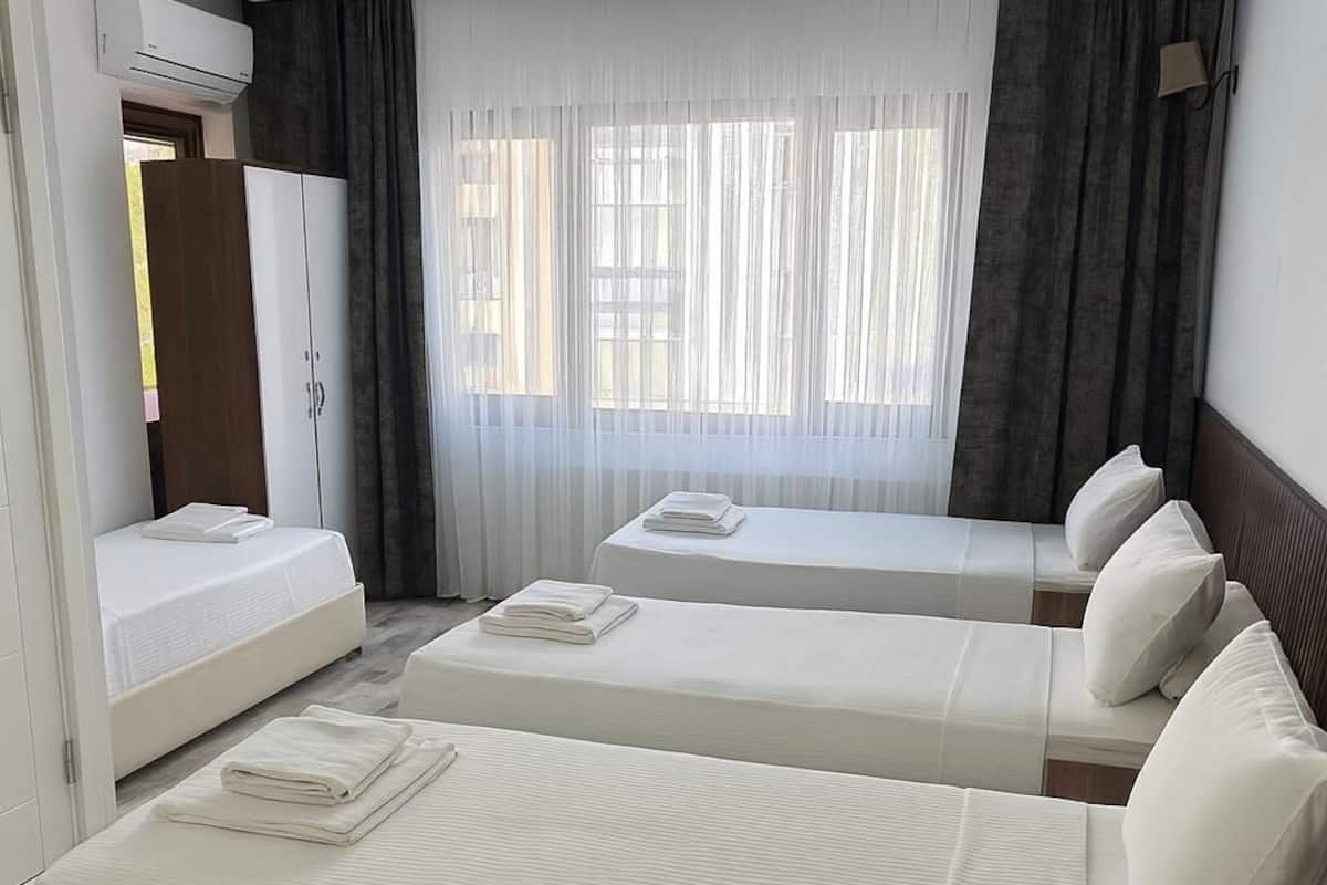 A hotel room with two single beds, a wardrobe, and a window with curtains.