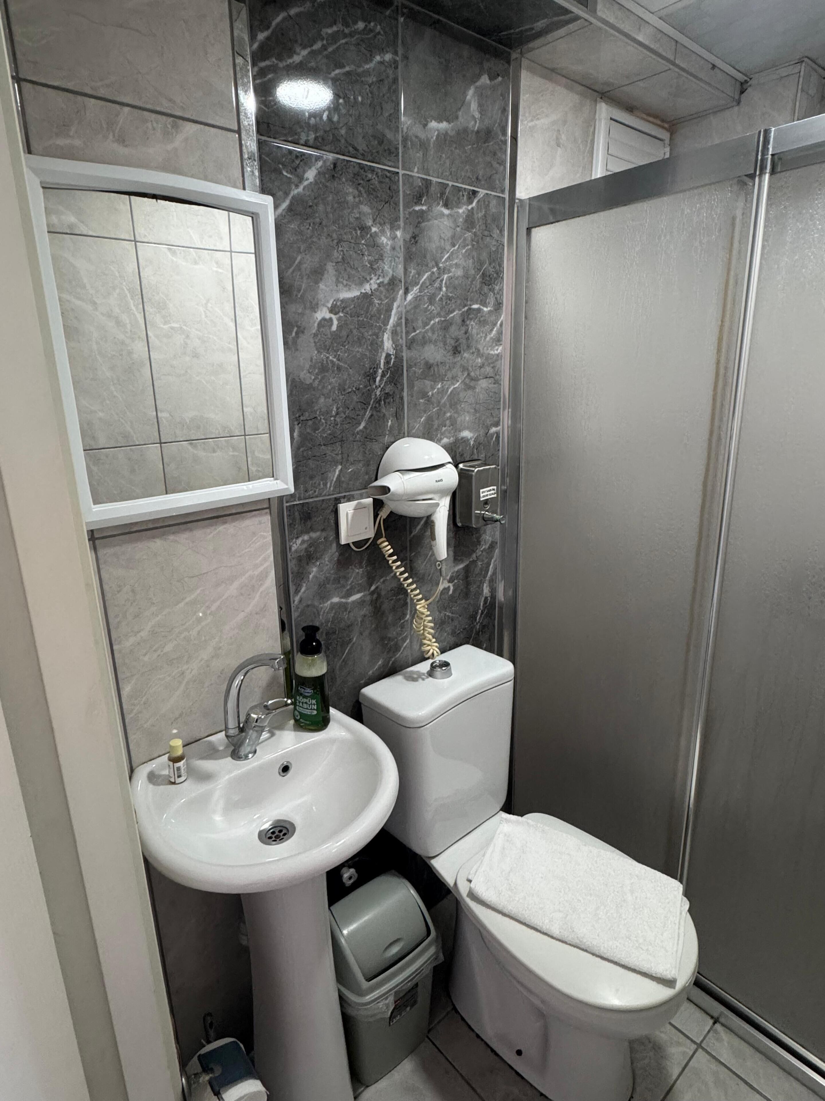 Et badeværelse med en hvid vask, toilet og brusebad.