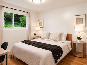 Ein ordentlich eingerichtetes Schlafzimmer mit Bett, Nachttischen, Lampen und gerahmten Bildern an den Wänden.