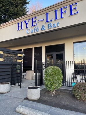 Ein Café und eine Bar namens HYE-LIFE mit moderner Fassade, einem verschlossenen Eingang und Außenplätzen.