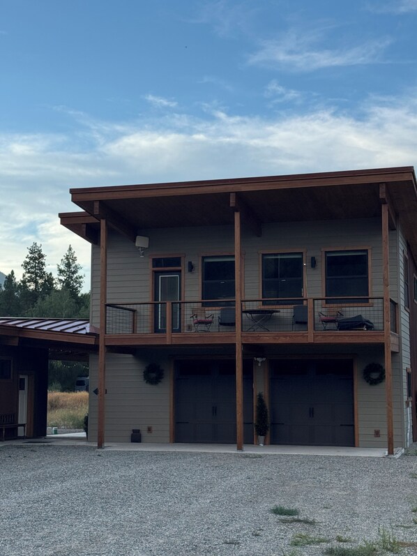 Un bâtiment à deux étages doté d’un porche avant couvert, d’un garage et d’un balcon avec un espace salon extérieur.