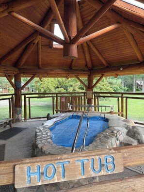 A hot tub under a wooden pavilion with a sign reading 'HOT TUB'.