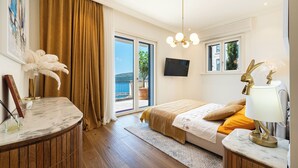 Ein Schlafzimmer mit Bett, Schreibtisch, Fernseher und Blick ins Freie.