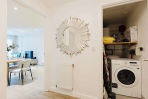 A laundry room with a washing machine, a mirror, and a radiator. - Stylish 1BDR Flat with Private Balcony in Vauxhall (London)