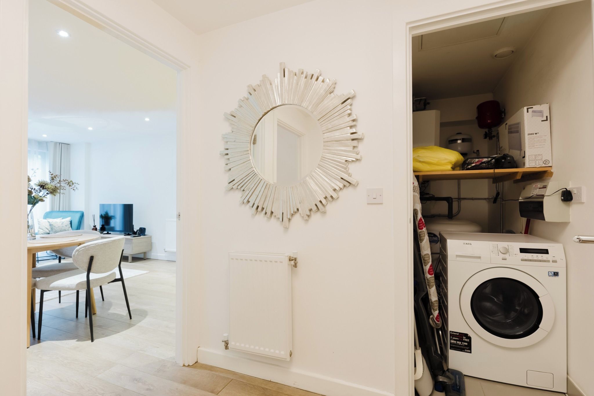 A modern kitchen with a built-in washing machine and a large decorative mirror.