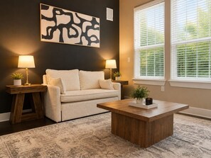 A living room with a sofa, two lamps, a coffee table, and a large abstract painting on the wall.