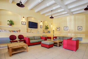 Una sala de estar con un sofá modular, una mesa de centro y un televisor.