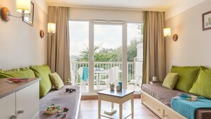 A room with a bed, a desk, a chair, and a balcony with curtains. - Branville Duplex Apartment for 6 (Branville)