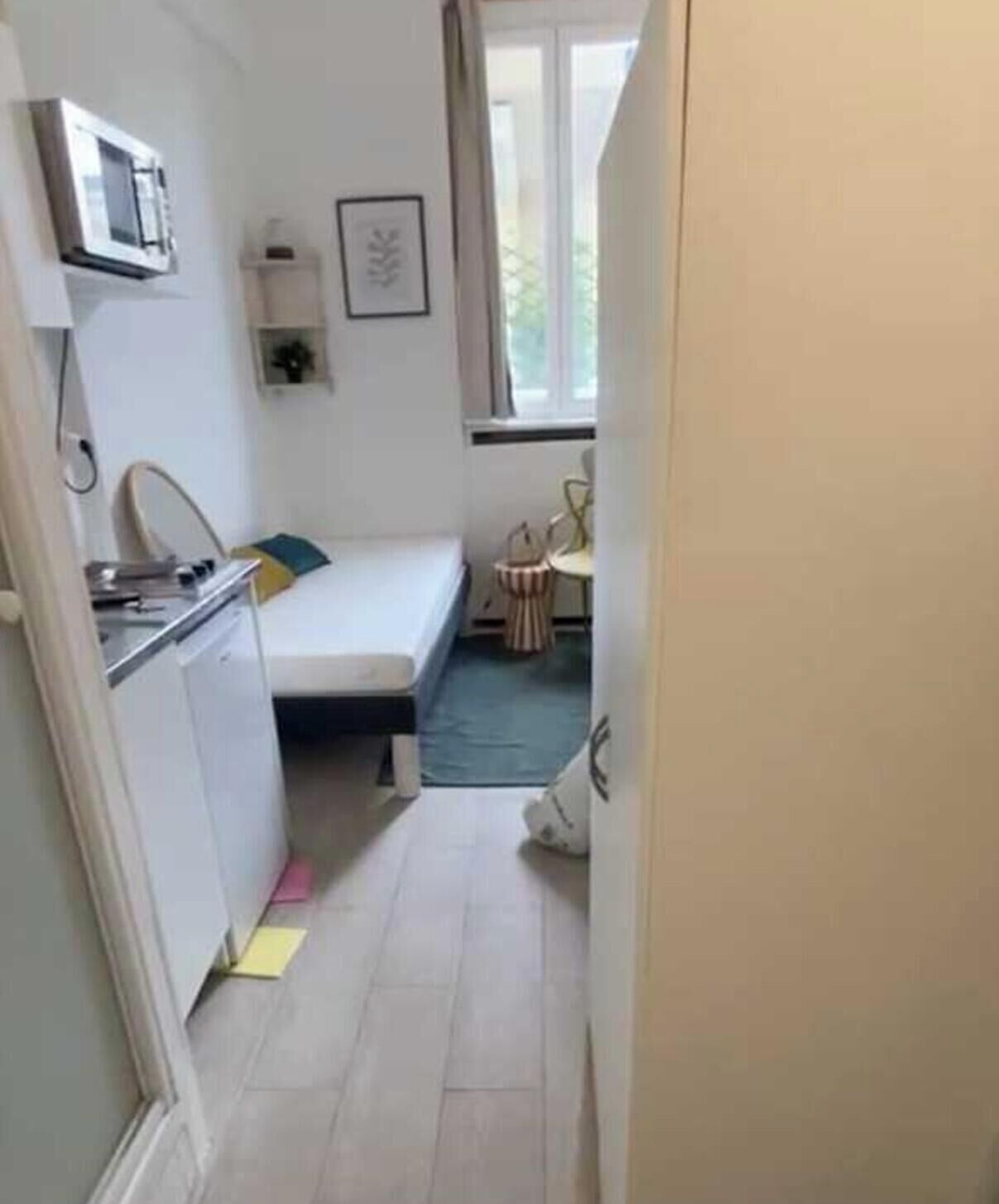 A small, compact room with a kitchenette, a bed, and a small table.