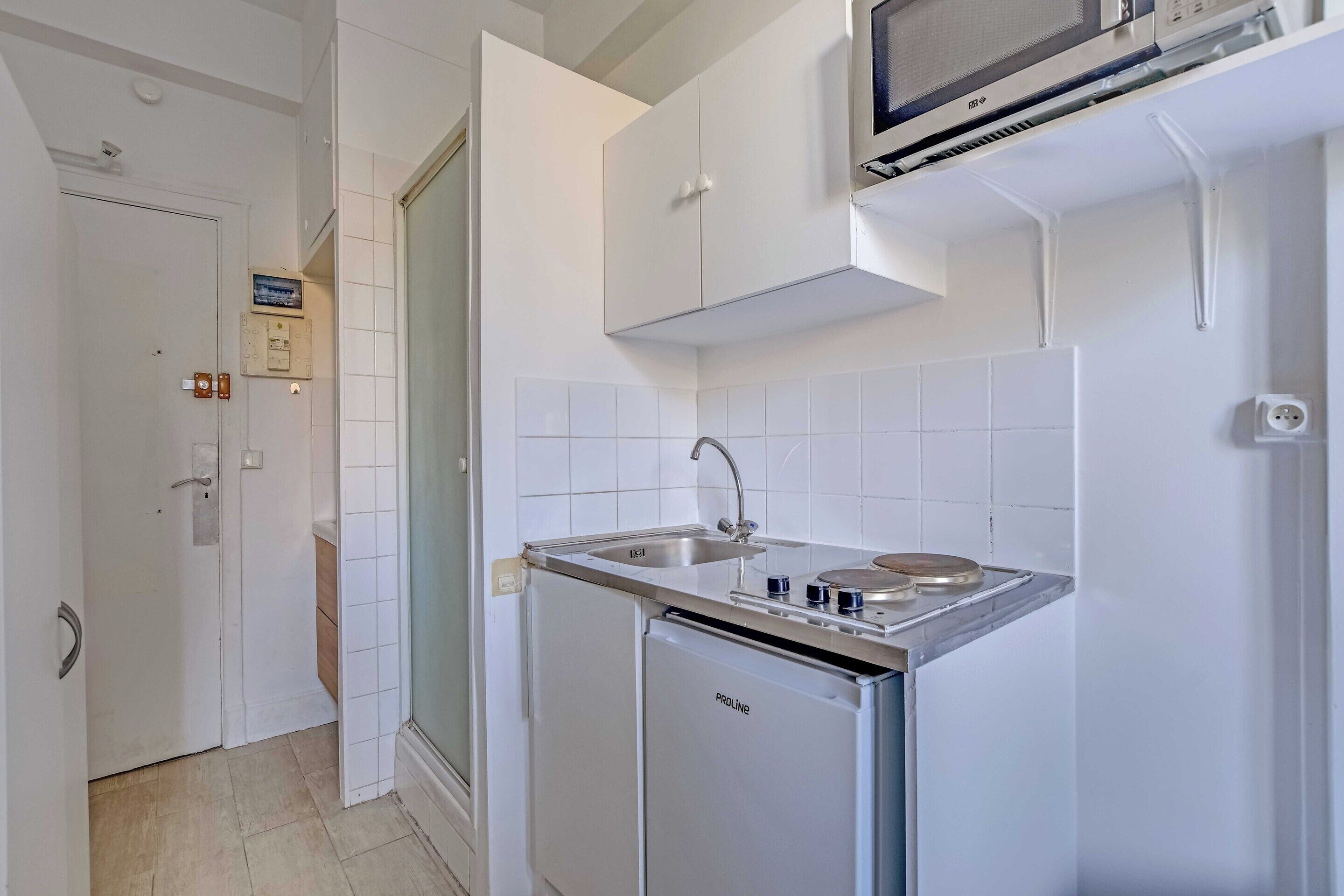 A compact kitchen with a built-in microwave, a sink, and a compact refrigerator.
