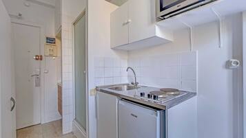 A compact kitchen with a built-in microwave, a sink, and a compact refrigerator.