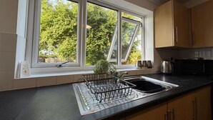 A kitchen with a large window, a sink, and wooden cabinets. - Swan View House in Littleport (Littleport)
