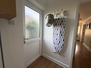 Ein Zimmer mit einer Tür aus Frostglas, einem gemusterten Vorhang, einem an der Wand befestigten Wäscheständer und einem Holzboden.