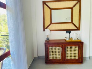 Une pièce comprenant un meuble en bois, un miroir avec un cadre géométrique, une lampe et une machine à café posée sur un plateau.