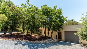 A modern house with a gravel driveway, trees, and a garage. - Villa Joy Pool Sauna River Escape (Murviel-les-Beziers)