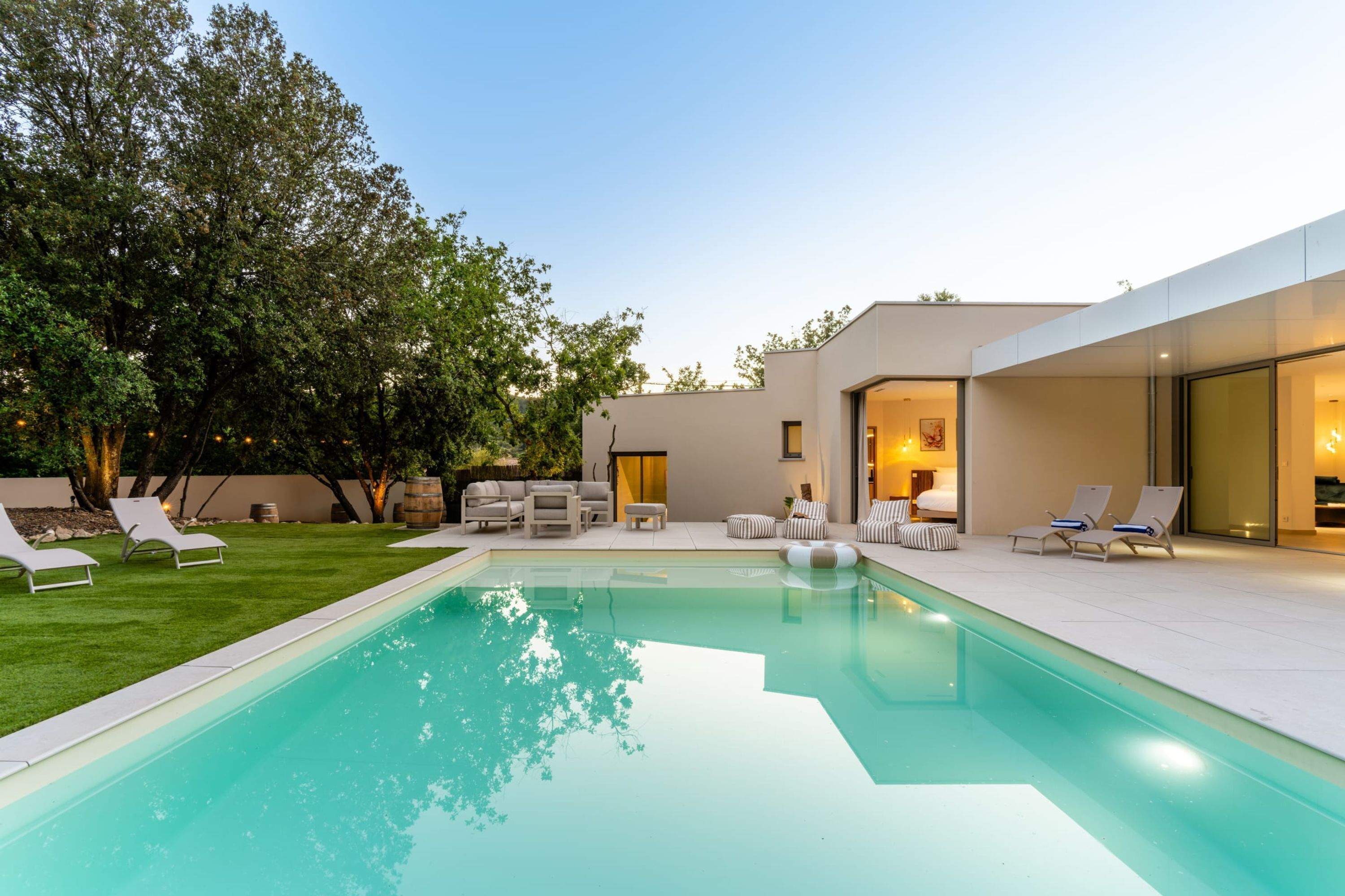 A modern pool area with lounge chairs and a well-maintained lawn.