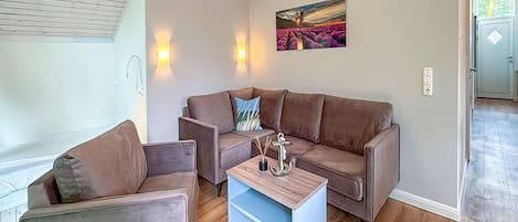 A living room with a brown sofa, a blue coffee table, and a painting on the wall.