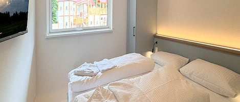 A bedroom with a bed, a window, and a nightstand.