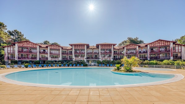 Un hĂŽtel dotĂ© dâune grande piscine, de nombreux balcons et offrant une vue sur un ciel dĂ©gagĂ©.