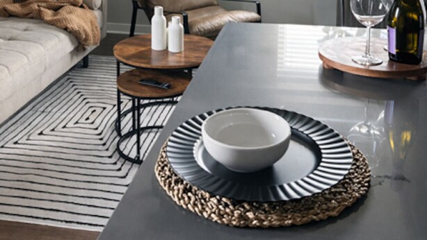 Een moderne woonkamer met een bank, fauteuil, salontafel en een eettafel met een schaal en wijnglas.