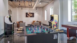 Een moderne binnenruimte met een tafelvoetbalspel, zithoek en een tafelvoetbal met een kleurrijk ontwerp.